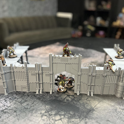 Scrap Fort wall line and gatehouse set up as a frontier defence on a 40k battle mat, unpainted grey PLA with ork miniatures on the parapet