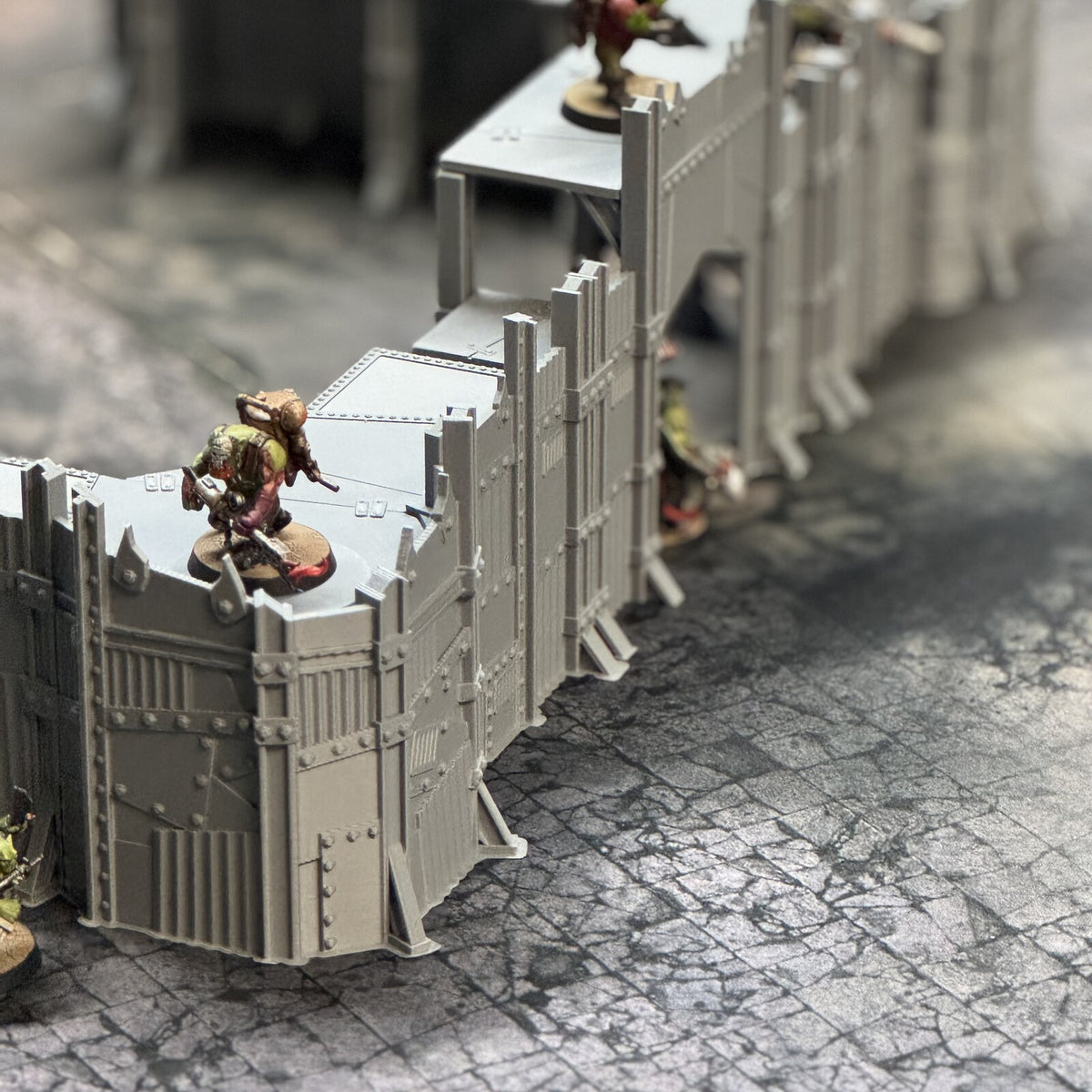 Scrap Fort wall sections with elevated fighting platforms, a miniature standing on the parapet walkway